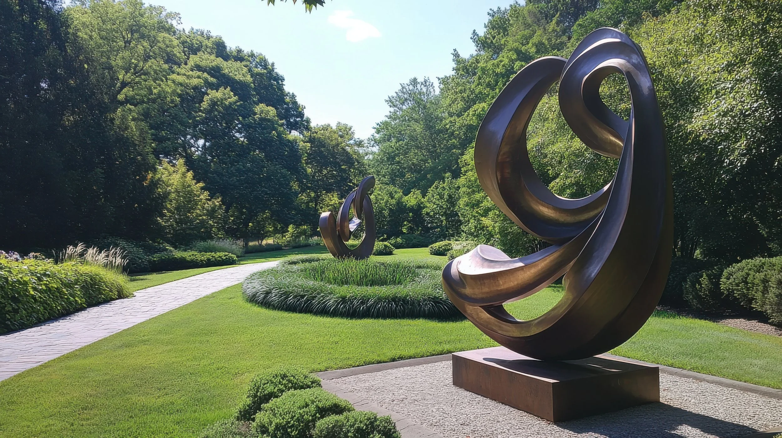 Two bird-shaped stone sculptures sit on a large rock beside a pond with lily pads and blooming water lilies, surrounded by tall grass and plants.