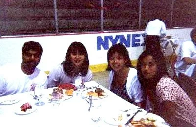 Four people sitting at a table with plates of food, in an indoor setting with a NYSE banner in the background.