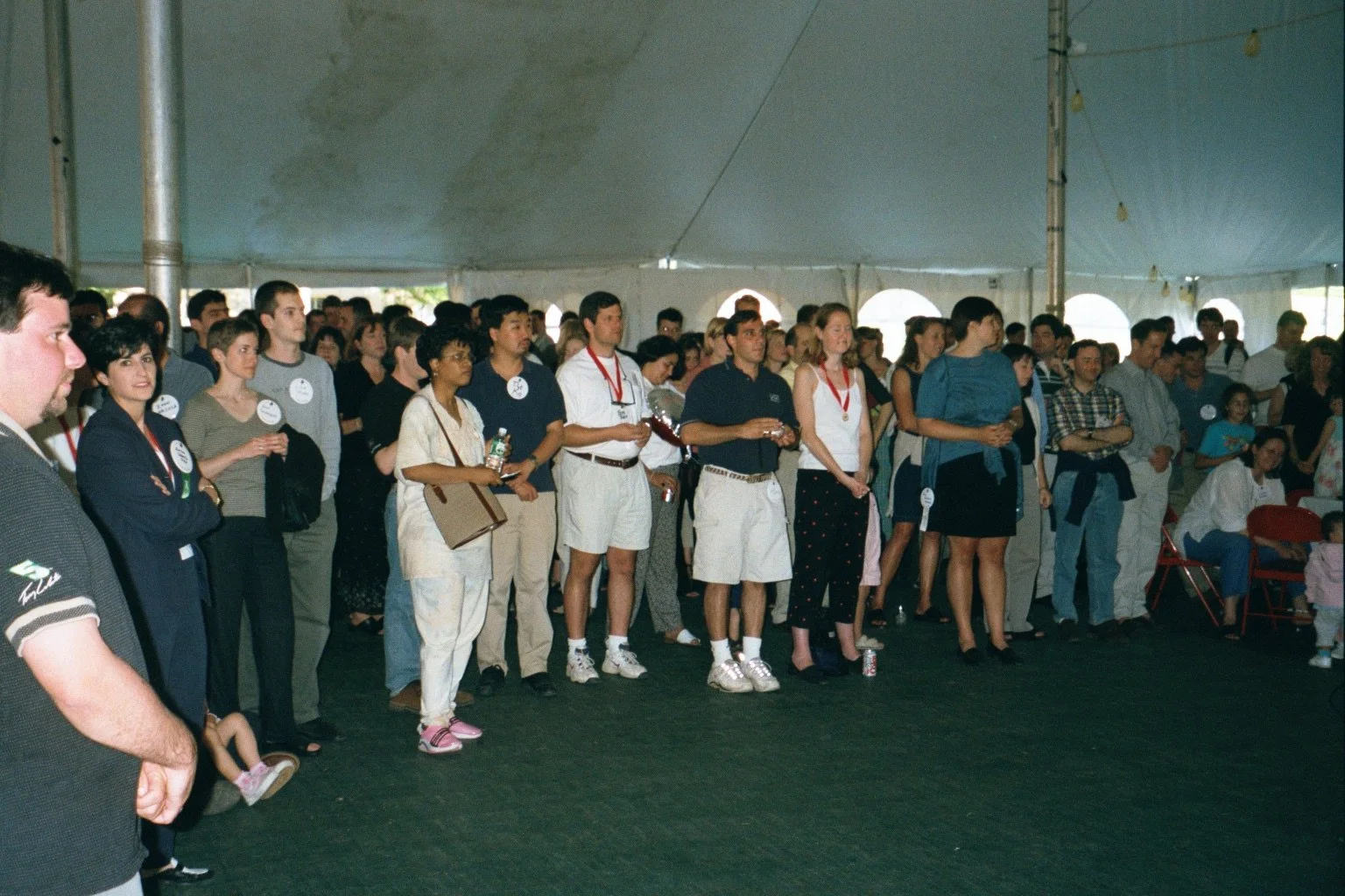 People standing in a line under a large event tent attending a formal gathering or conference.