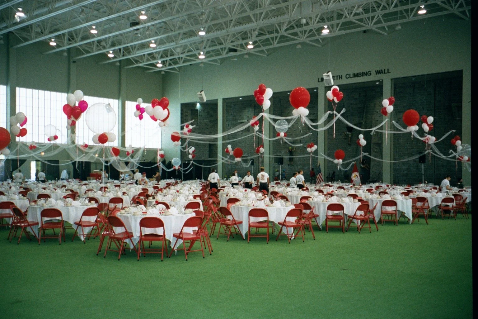 Ramin Room at Cornell during Cornell Reunion weekend, decorated with red, white, and pink balloons, white tablecloths, and red chairs, set up for an event with round tables and ceiling decorations.