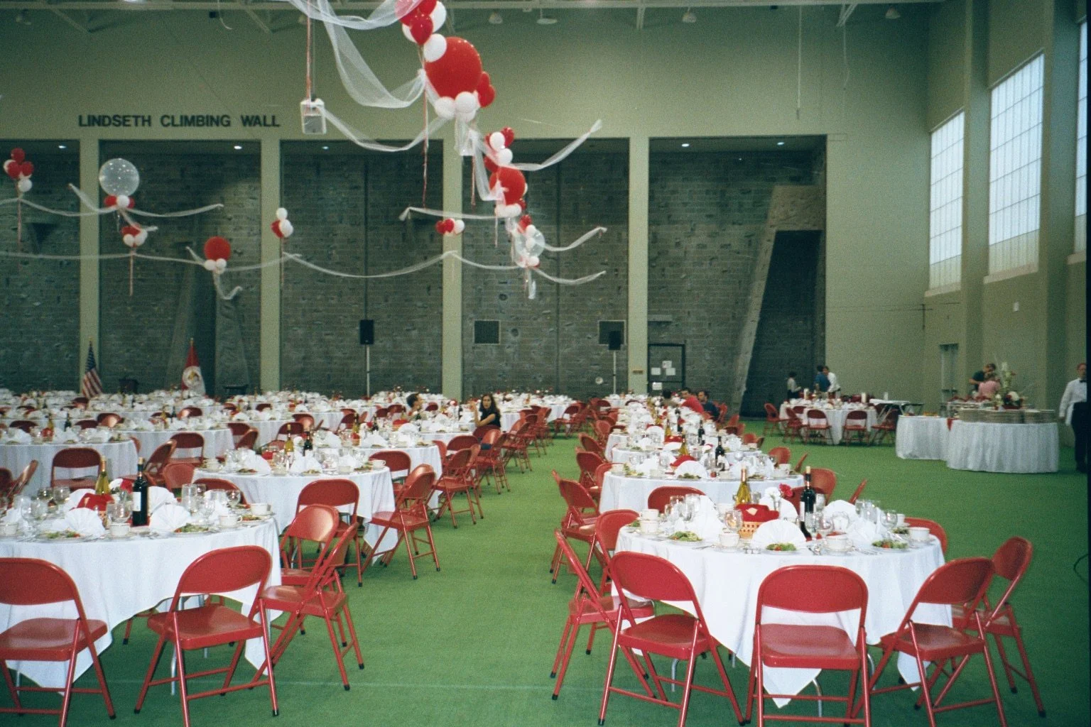Ramin Room at Cornell during Cornell Reunion weekend, decorated with white tablecloths, red chairs, and balloons, with an area called 'Lindseth Climbing Wall' in the background.