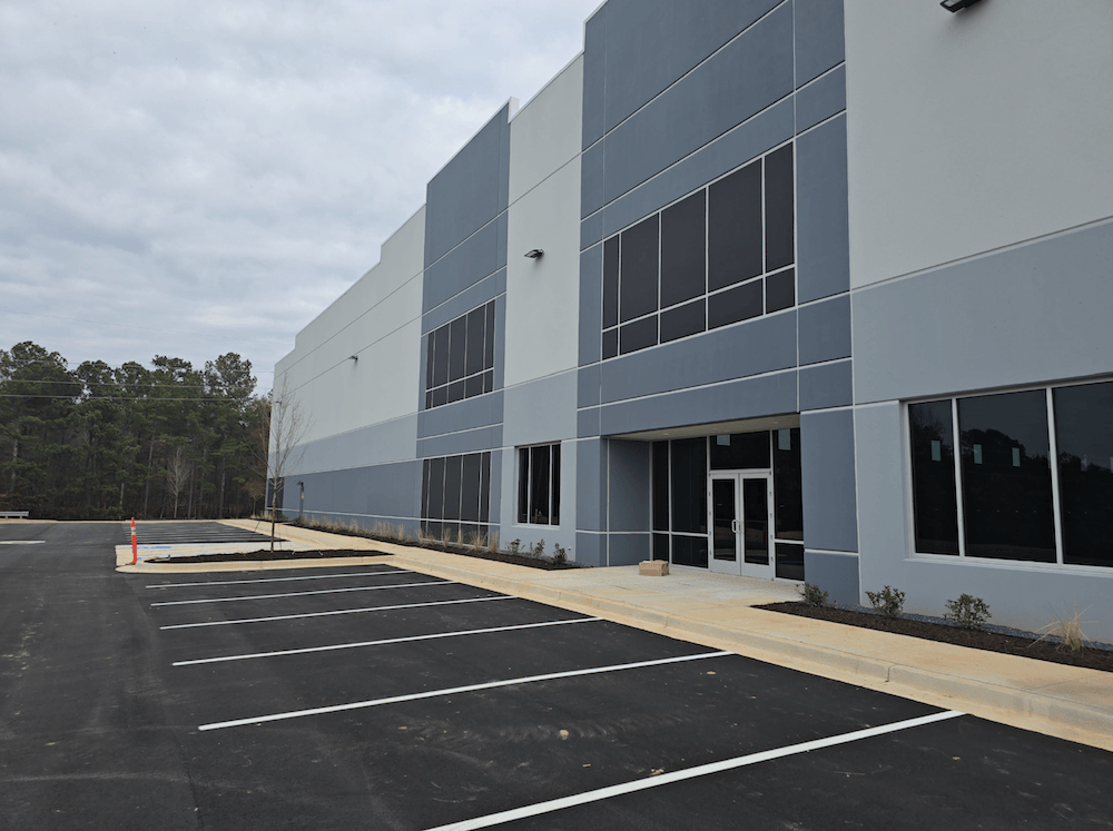 Modern commercial building with large windows and a parking lot in front.