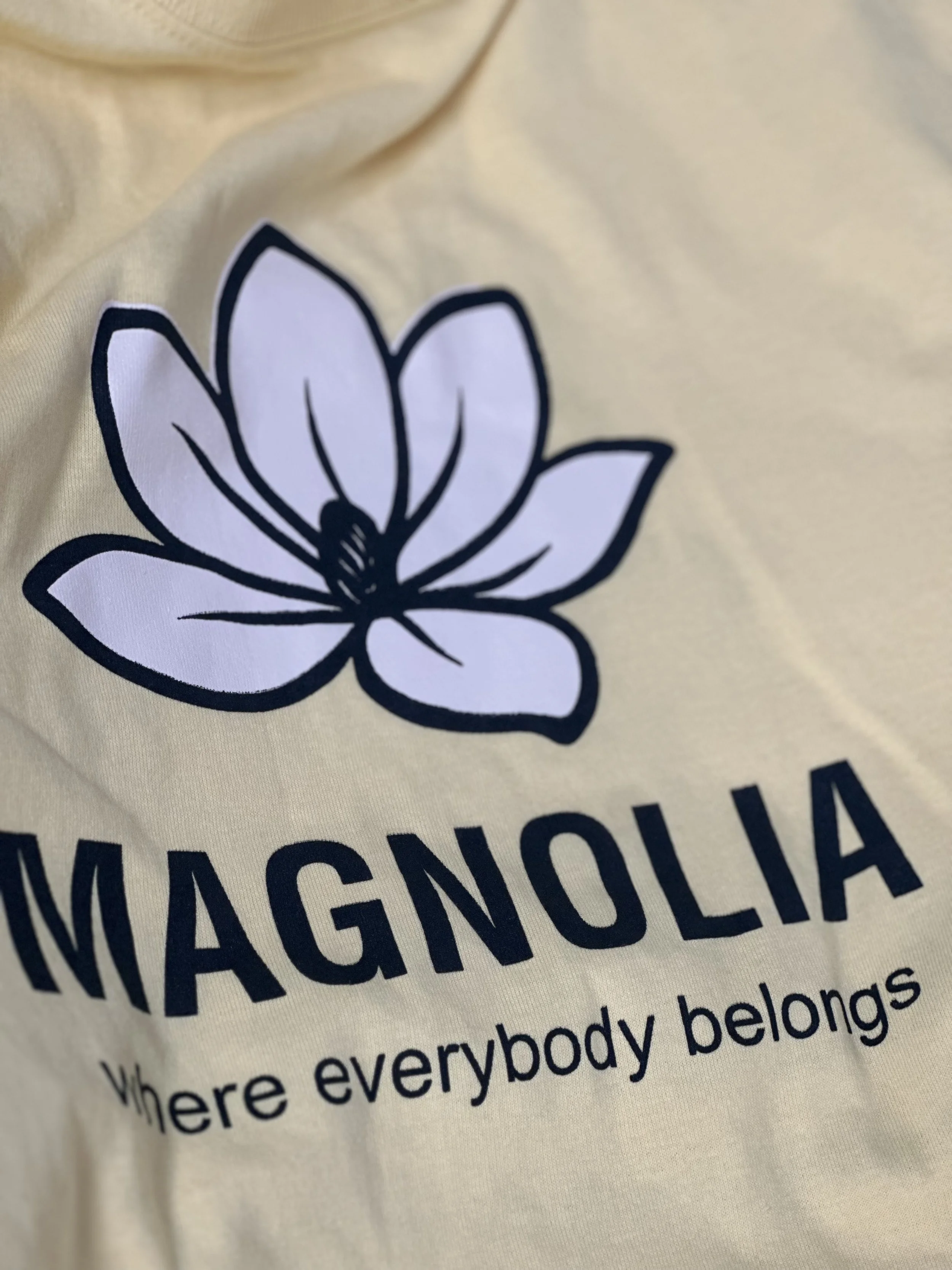 Close-up of a beige fabric with a black and white magnolia flower graphic and the text 'MAGNOLIA' and smaller text 'Where everybody belongs'.