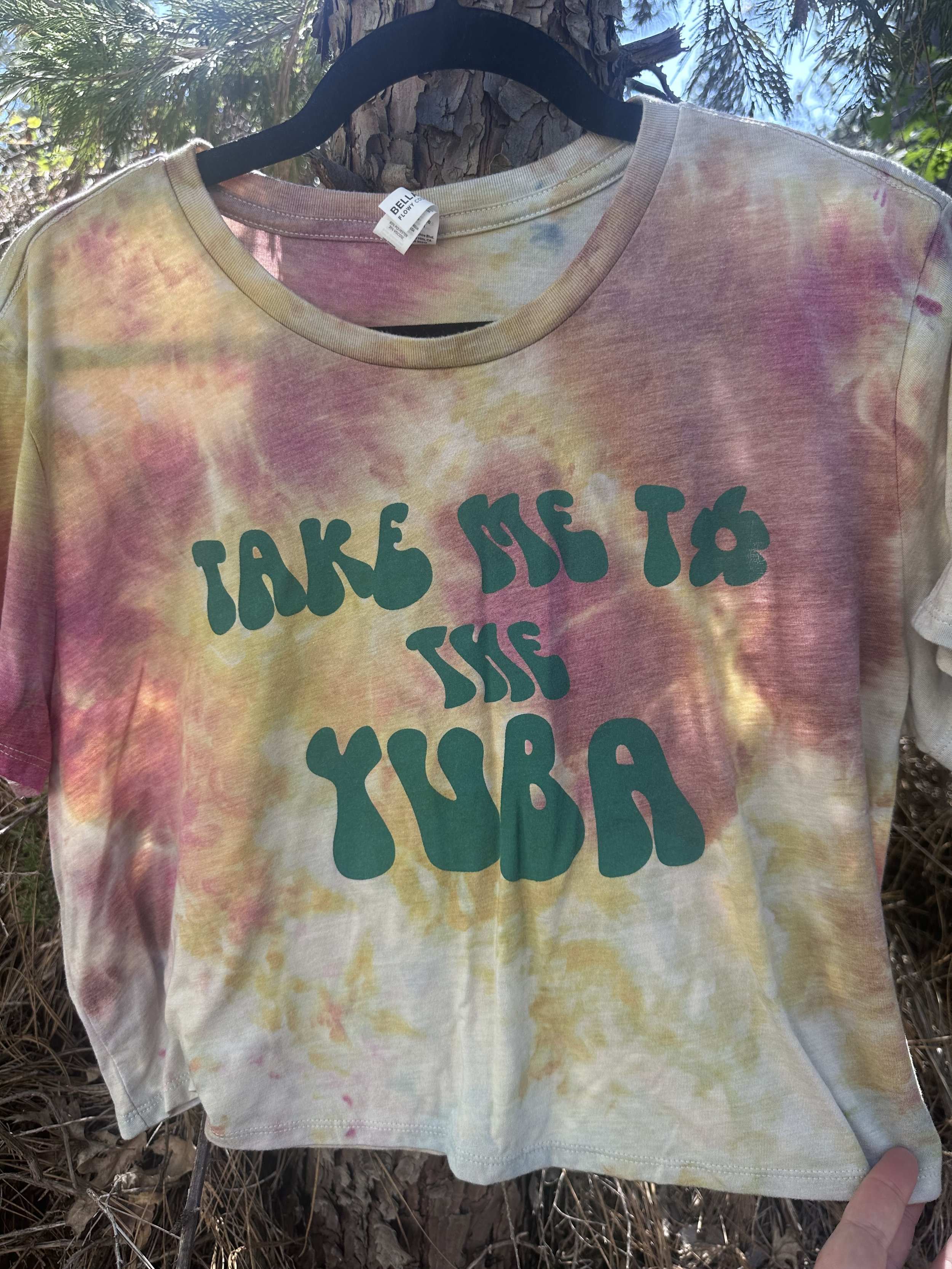 A tie-dye T-shirt with pastel colors and the phrase "Take me to the juice" printed in green text.