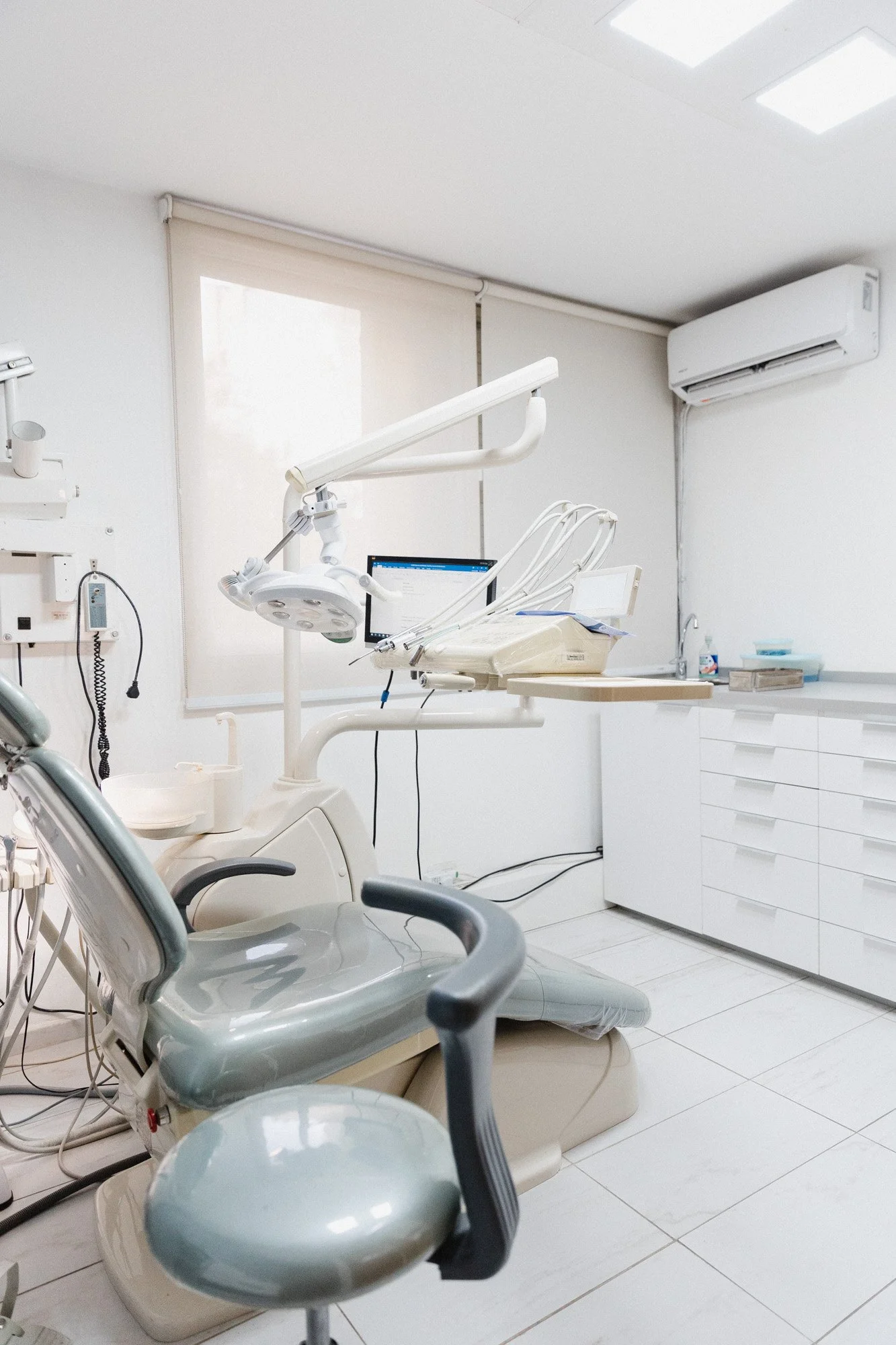 Silla y equipo dental en una clínica odontológica, con gabinetes y aparatos blancos en un ambiente limpio y moderno.