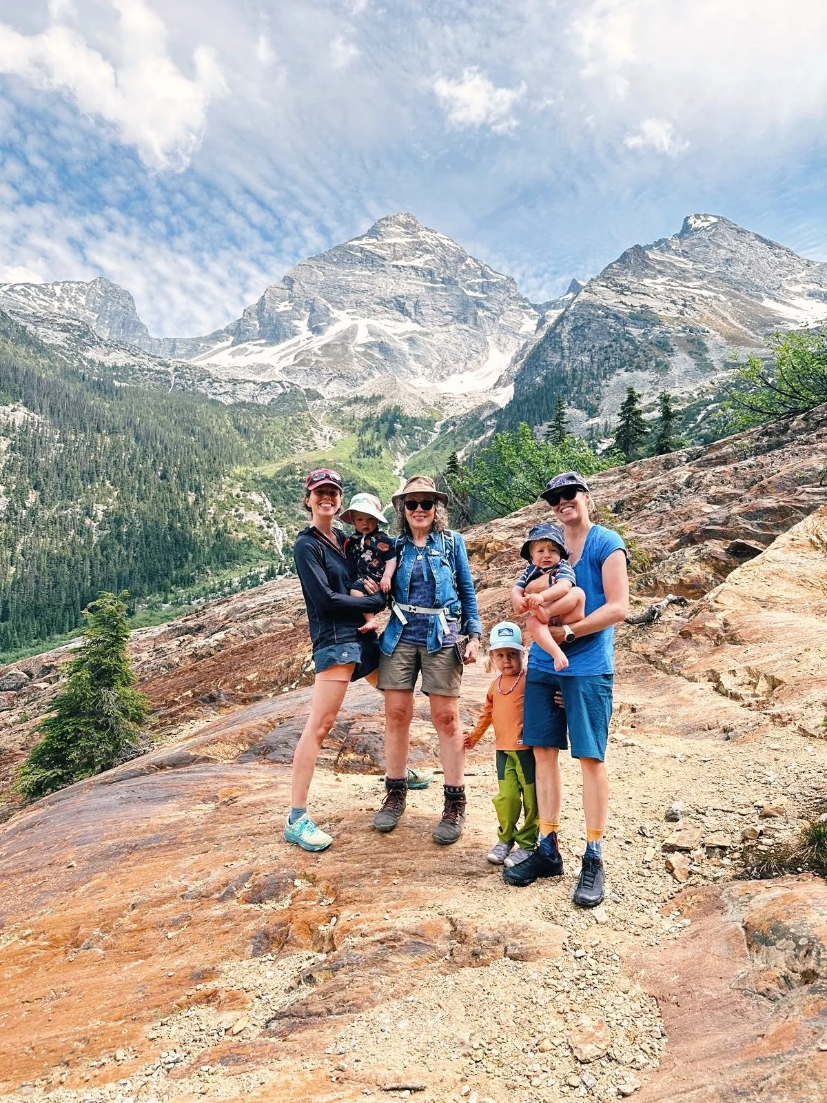 A family standing on Rocky Mountain terrain with big beautiful peak in background