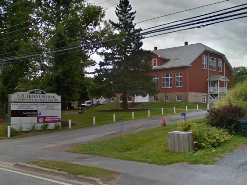 E.H. Horne School Community Activity Centre building with a sign, trees, and a street in the foreground.