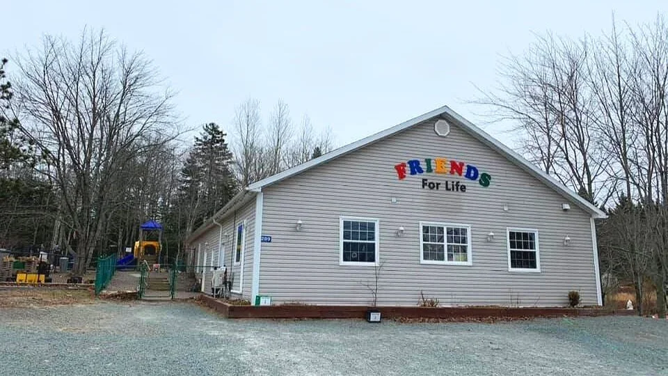 A single-story building with a sign that reads 'Friends For Life' in colorful letters, surrounded by leafless trees.