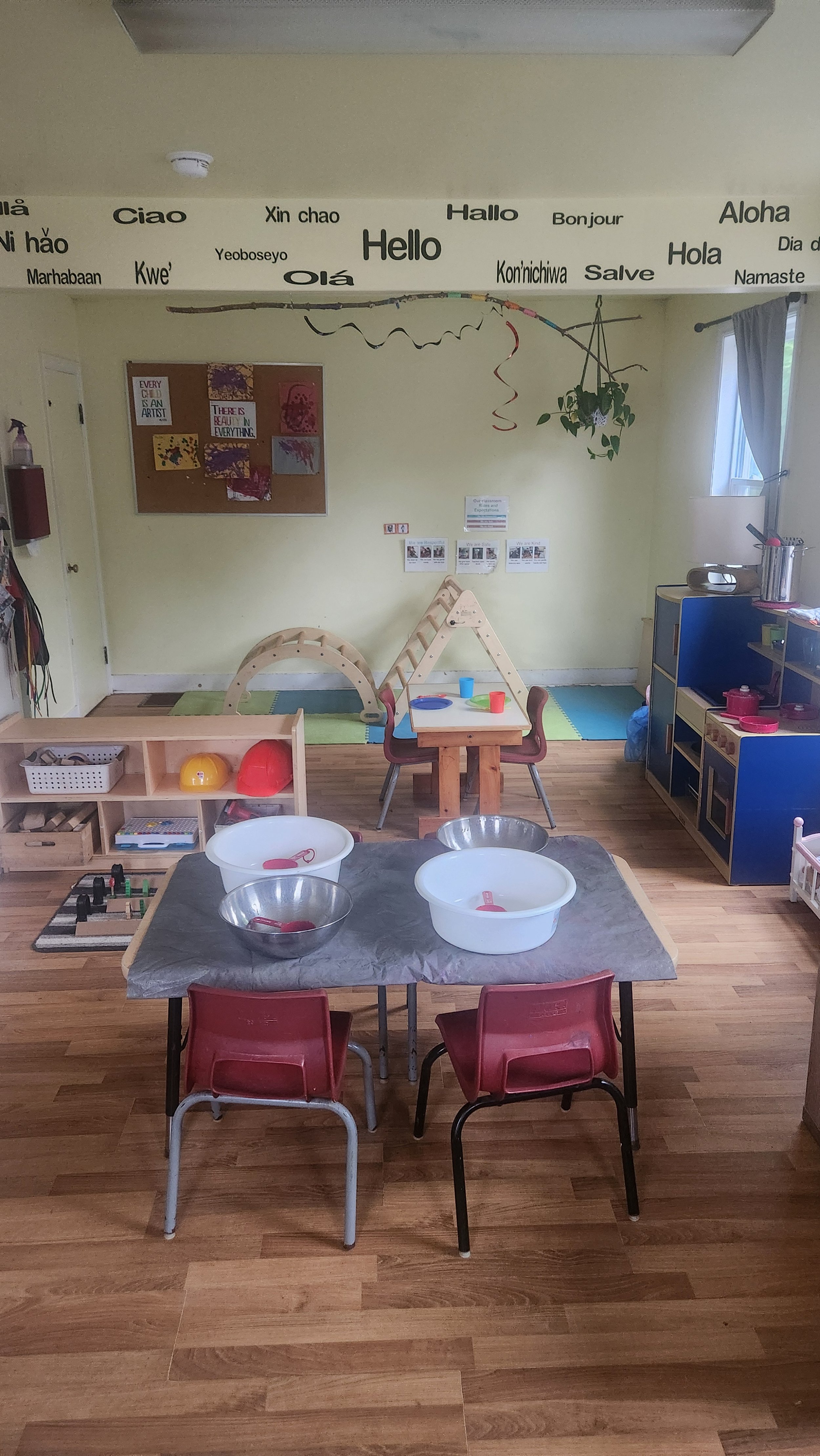 A colorful children's playroom and classroom with tables, chairs, toys, and educational materials.
