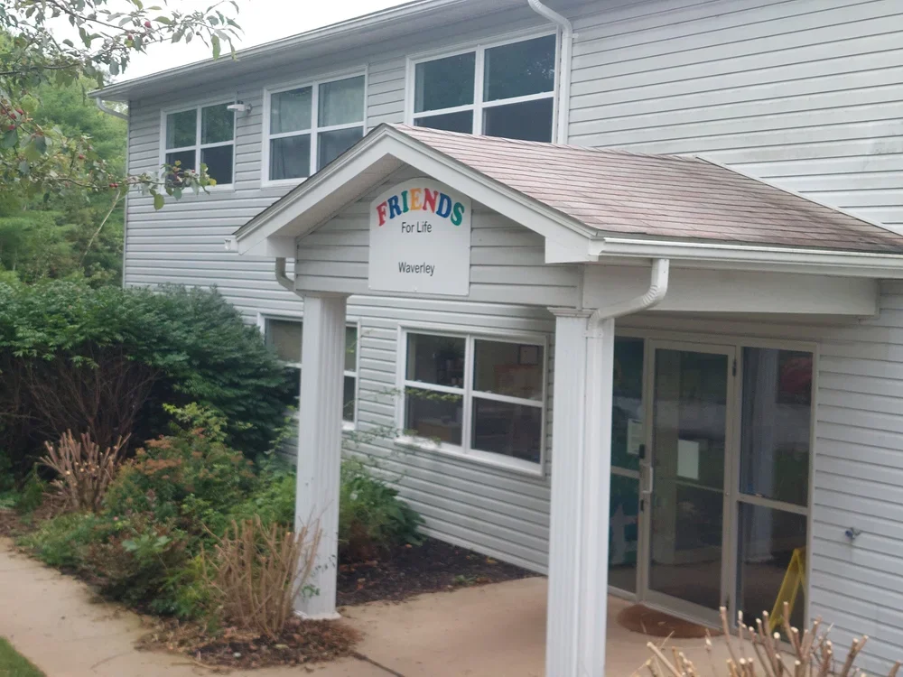 Exterior of a white building with a small porch and a sign reading "FRIENDS For Life Waverley" with colorful letters.