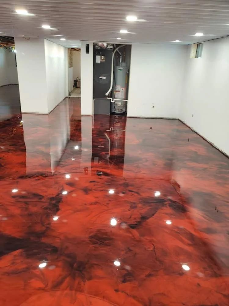 Underground room with polished, reddish-brown, marble-like epoxy flooring and white walls. A water heater is visible in a small alcove. The ceiling has recessed lighting and a small window is on the right wall.