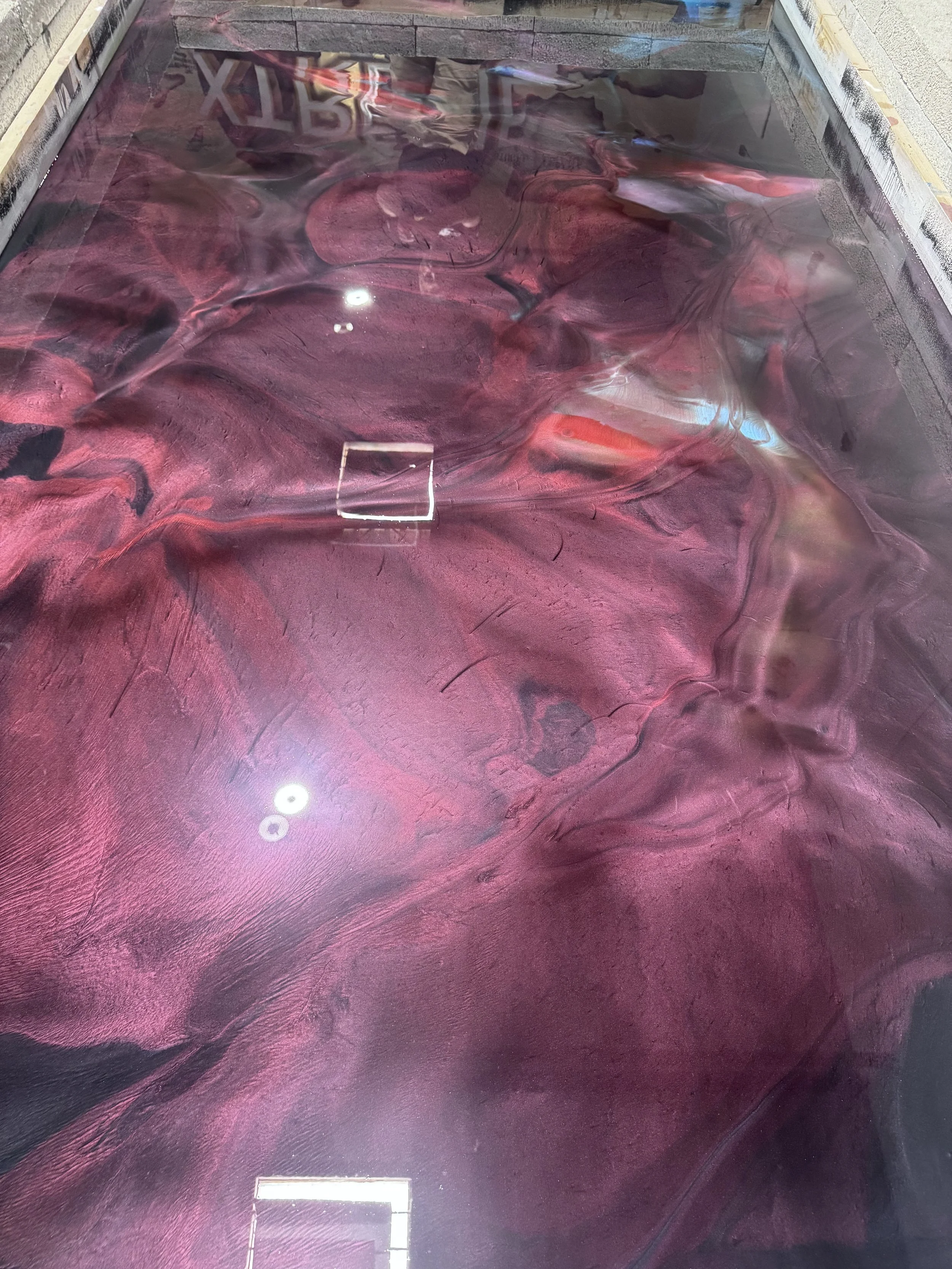 Close-up of a wooden surface with a glossy finish that reflects purple, pink, and blue colors.