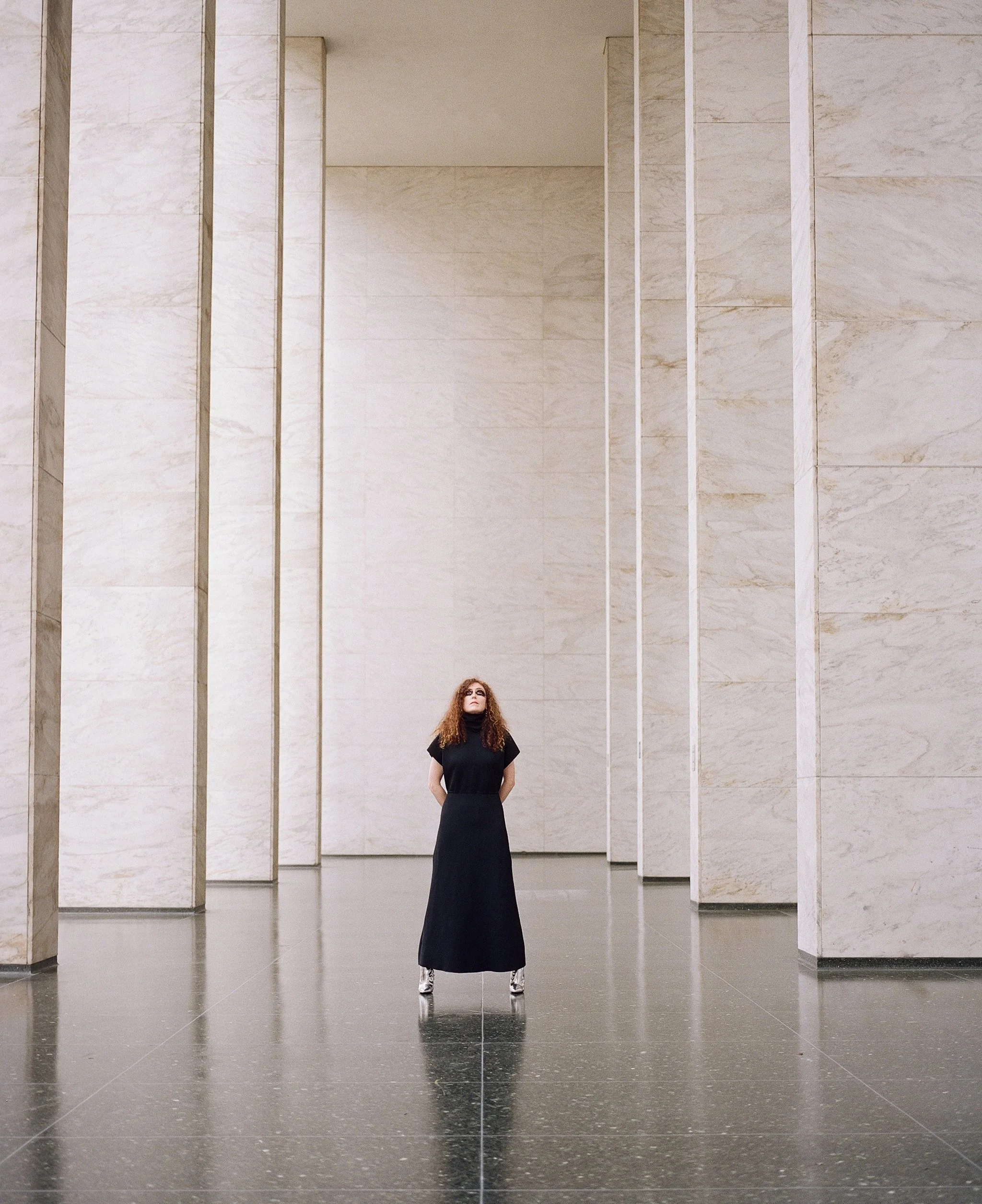 Film photograph — solitary figure in black dress standing beneath monumental marble columns in San Francisco, shot on analogue film by Radostina Boseva