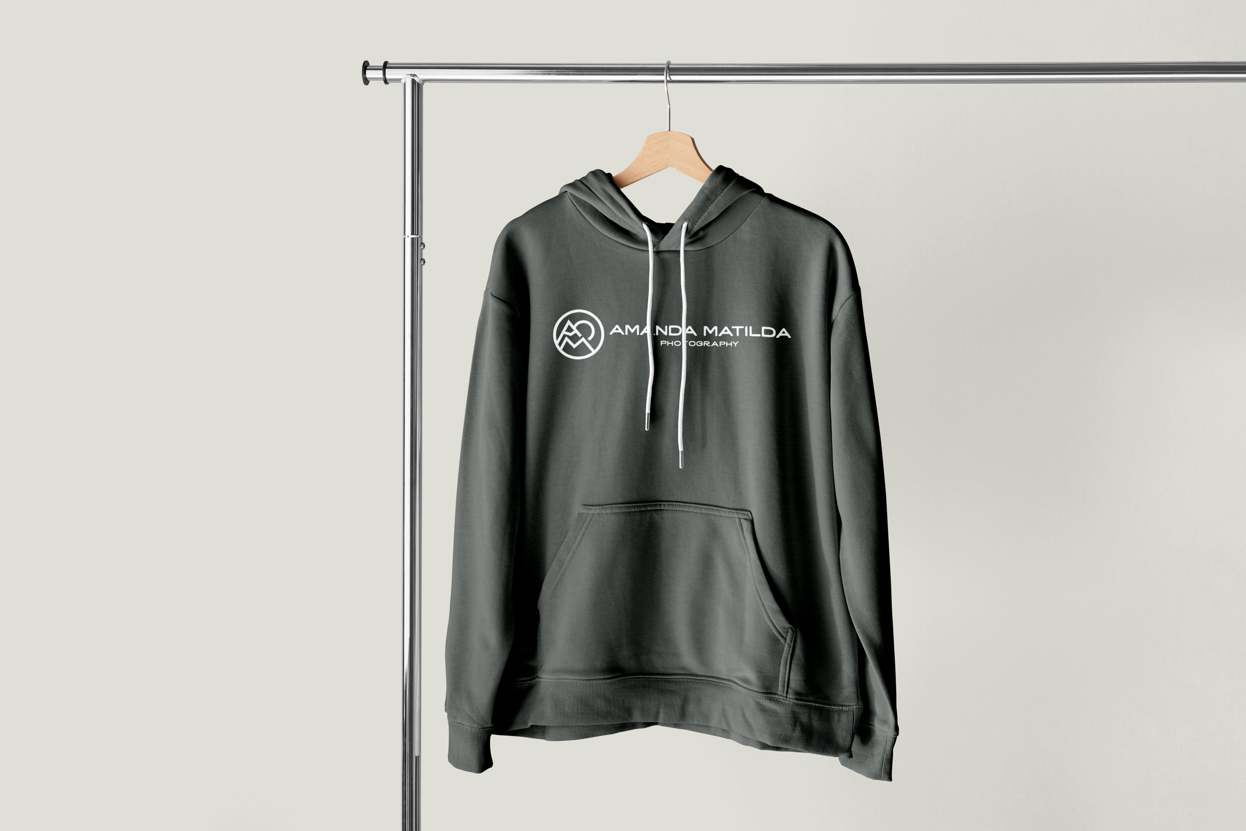 Gray hoodie with a white graphic and text, hanging on a wooden hanger on a metal clothing rack