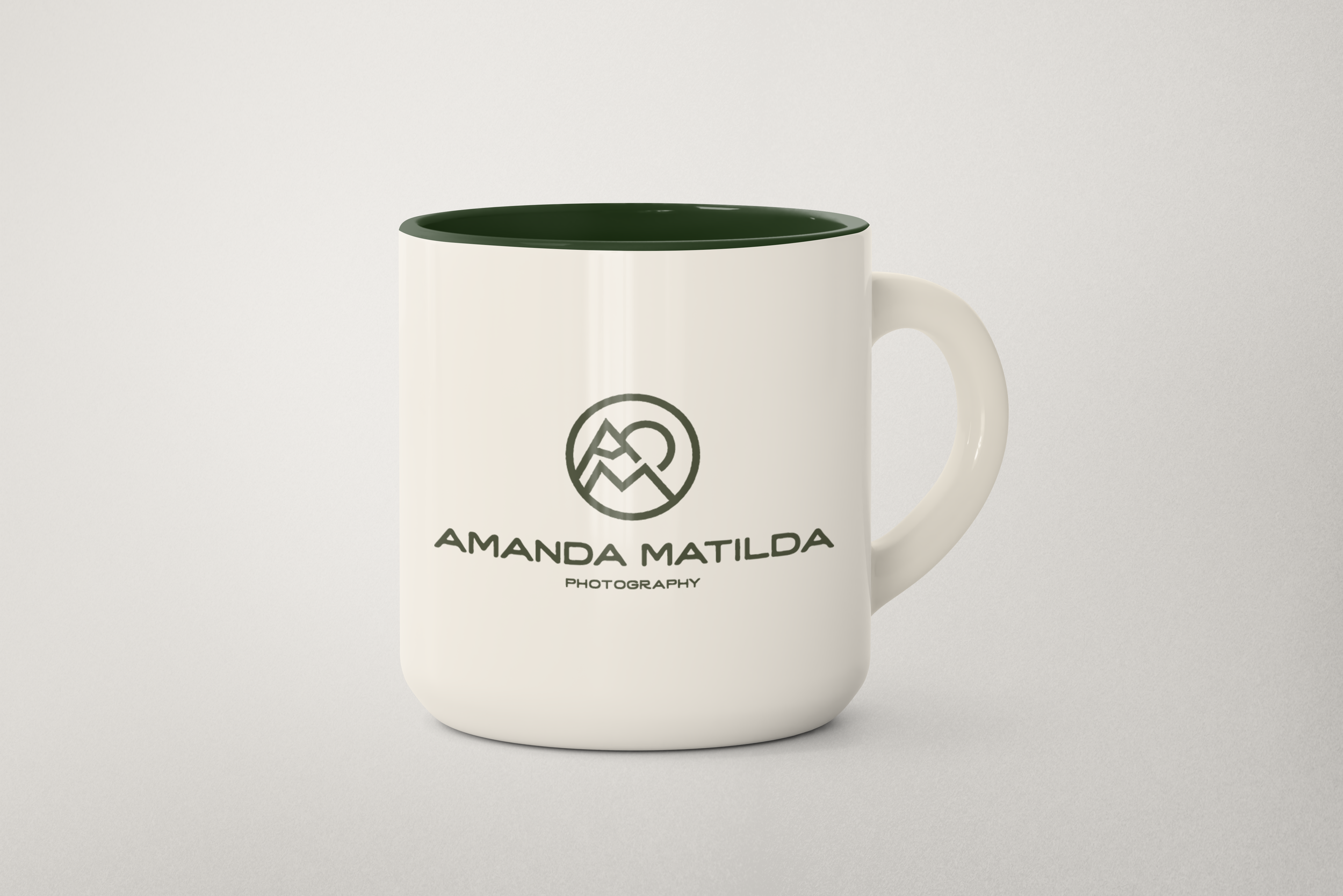 A white ceramic mug with a green interior and a black logo that reads 'AMANDA MATILDA PHOTOGRAPHY,' set against a light background.