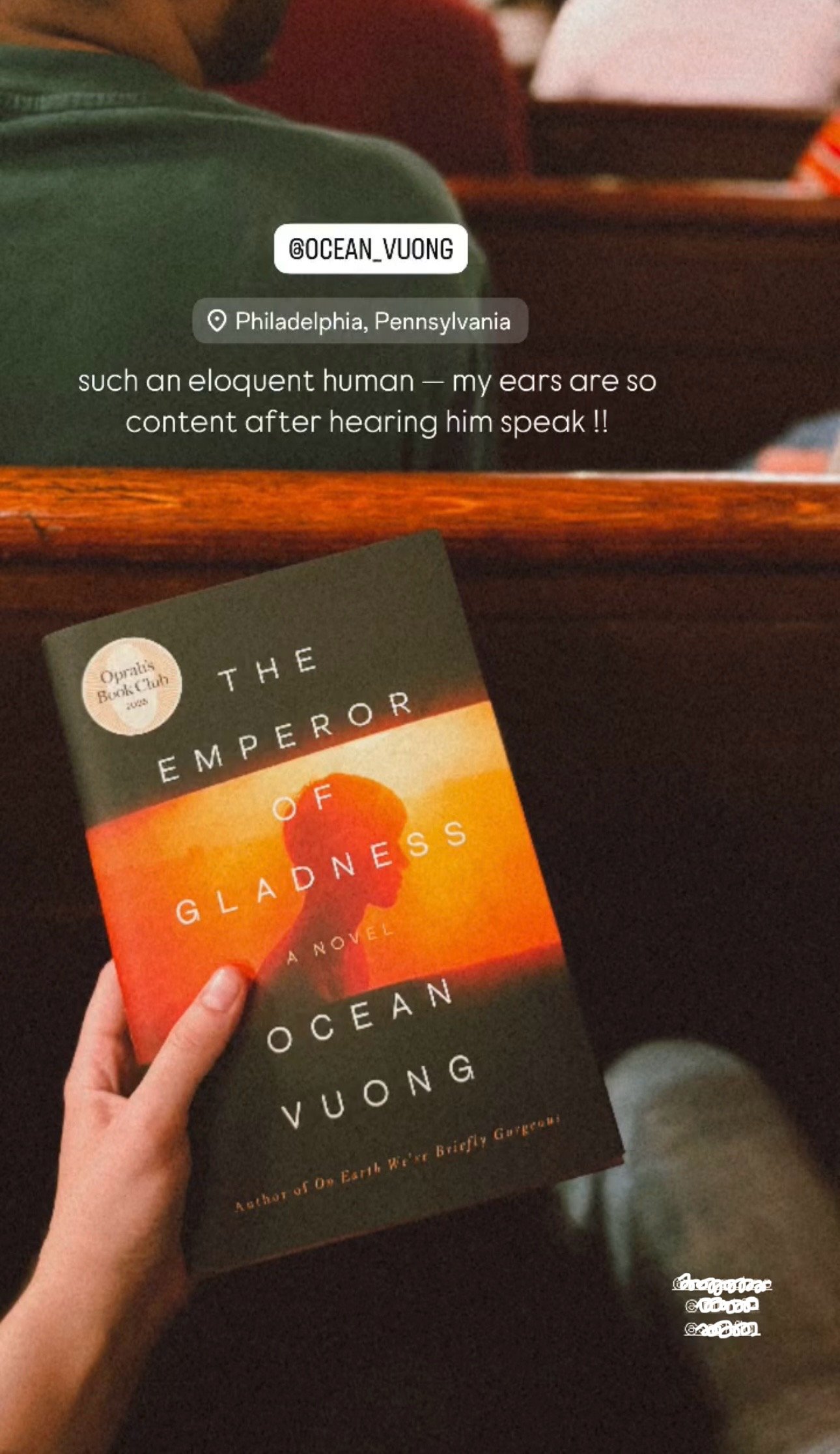 Person holding a copy of the book 'The Emperor of Gladness' by Ocean Vuong in a theater seat, with an audience in the background in Philadelphia, Pennsylvania.