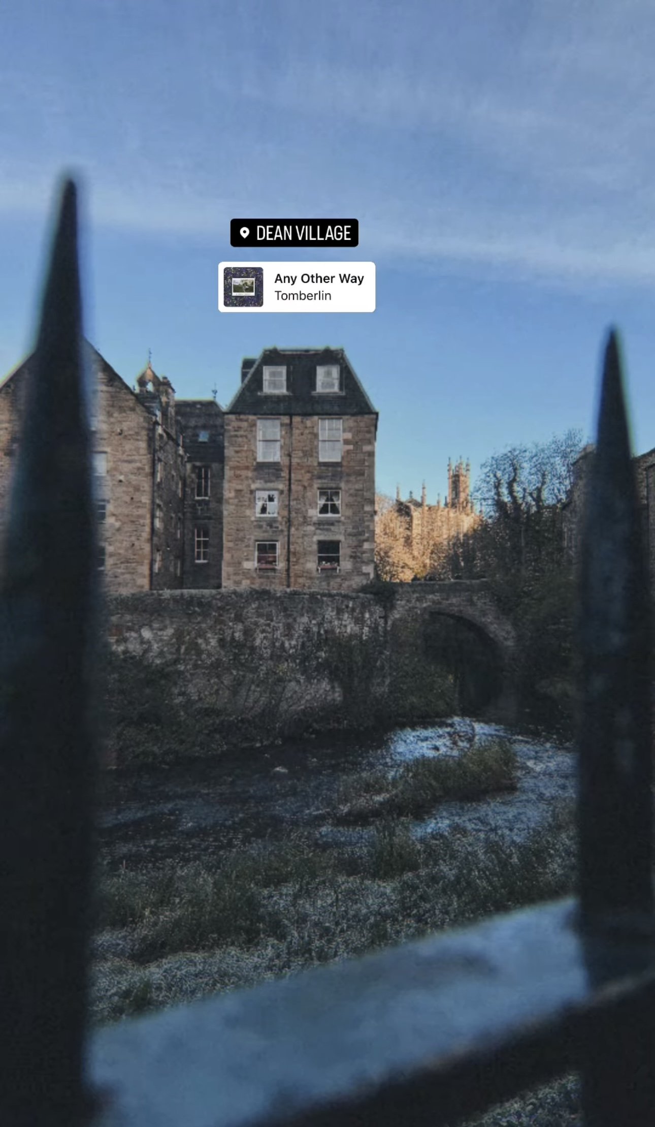 View of historic stone building with multiple windows in Dean Village, Edinburgh, Scotland, taken through a wrought iron fence.