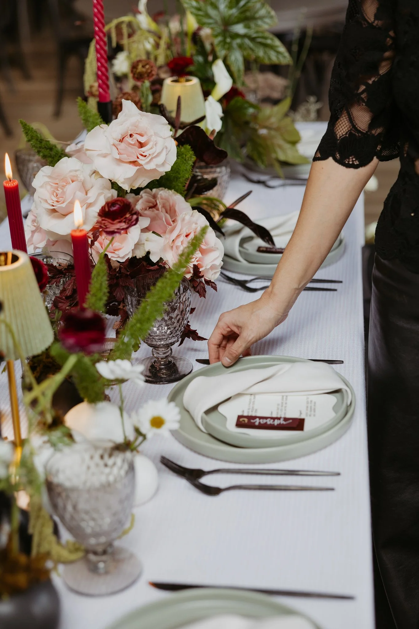 Michigan wedding planner styling reception table with floral centerpiece and layered place setting