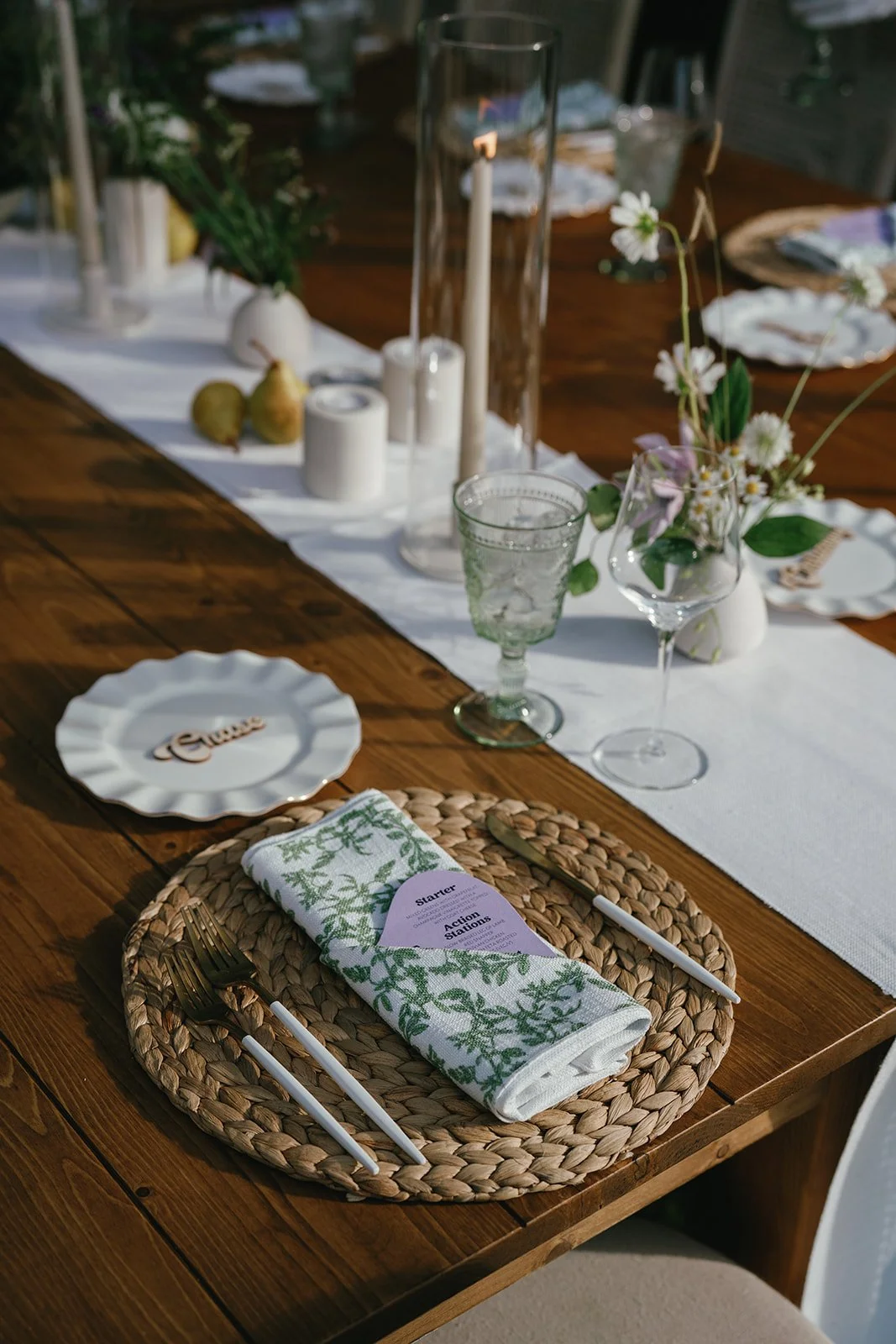 Intimate Michigan wedding reception table with woven charger, greenery napkin, and simple floral centerpieces.