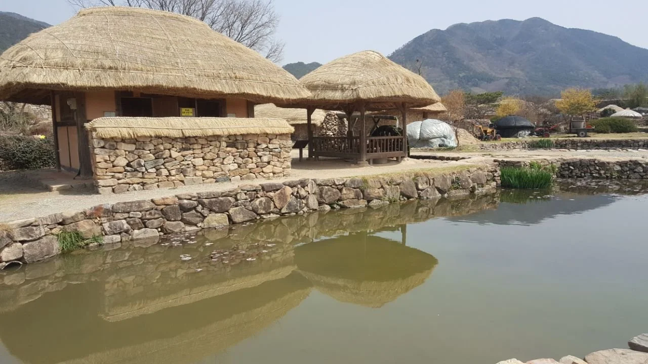 Thatched roof structures by a river taken by Intent Platform