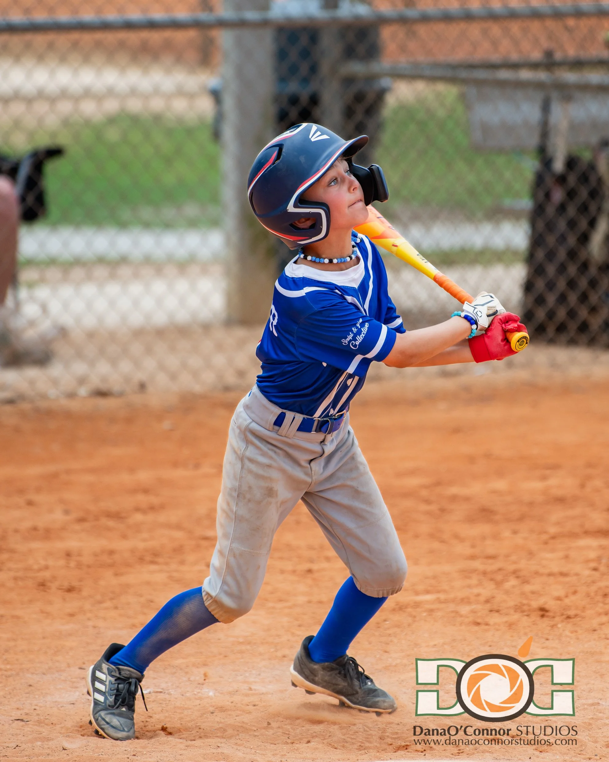 A young baseball player wearing a helmet and uniform swinging a bat on the baseball field during a game.