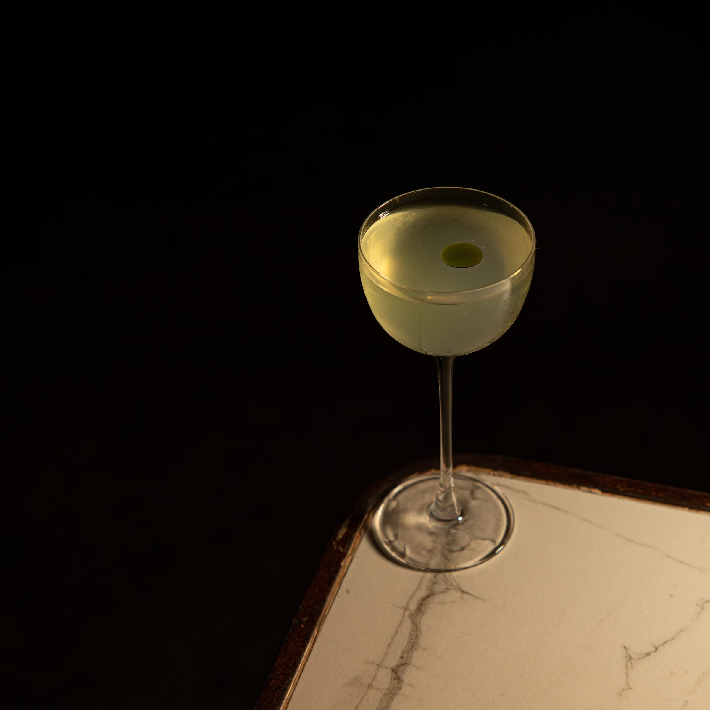 Coctel Monje claro en copa coupe con aceituna, servido en la barra de Mecenas