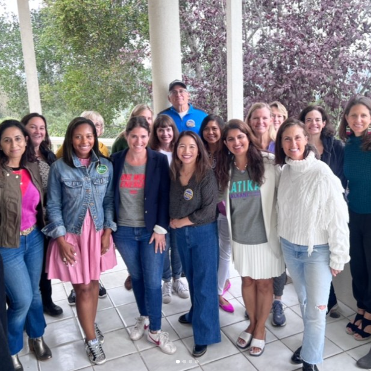 Group of people smiling on a porch with trees in the background at an election party in Orinda