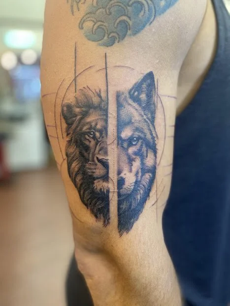 Tattoo of a lion's face on the left and a wolf's face on the right, divided by geometric lines on upper arm.