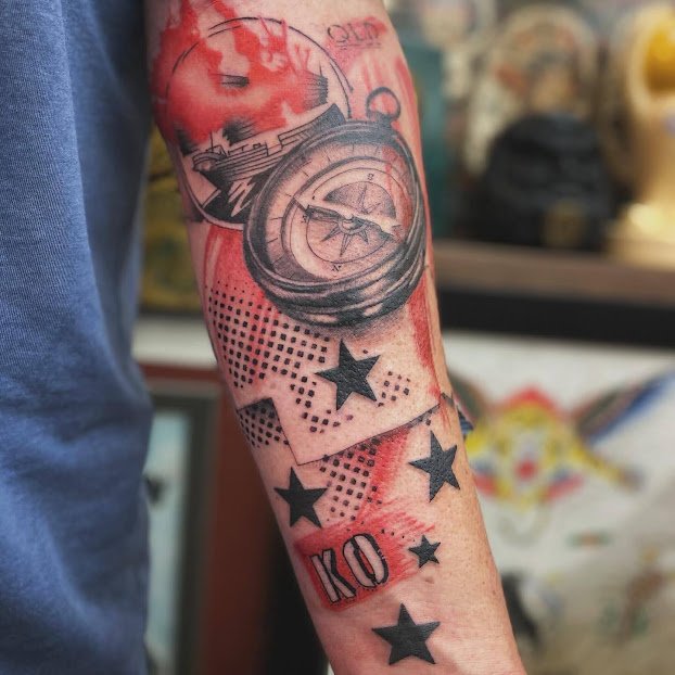 Tattoo of a pocket watch, playing cards, and stars on a person's arm.
