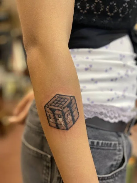 Person with a tattoo of a Minecraft-style wooden wither on their forearm.