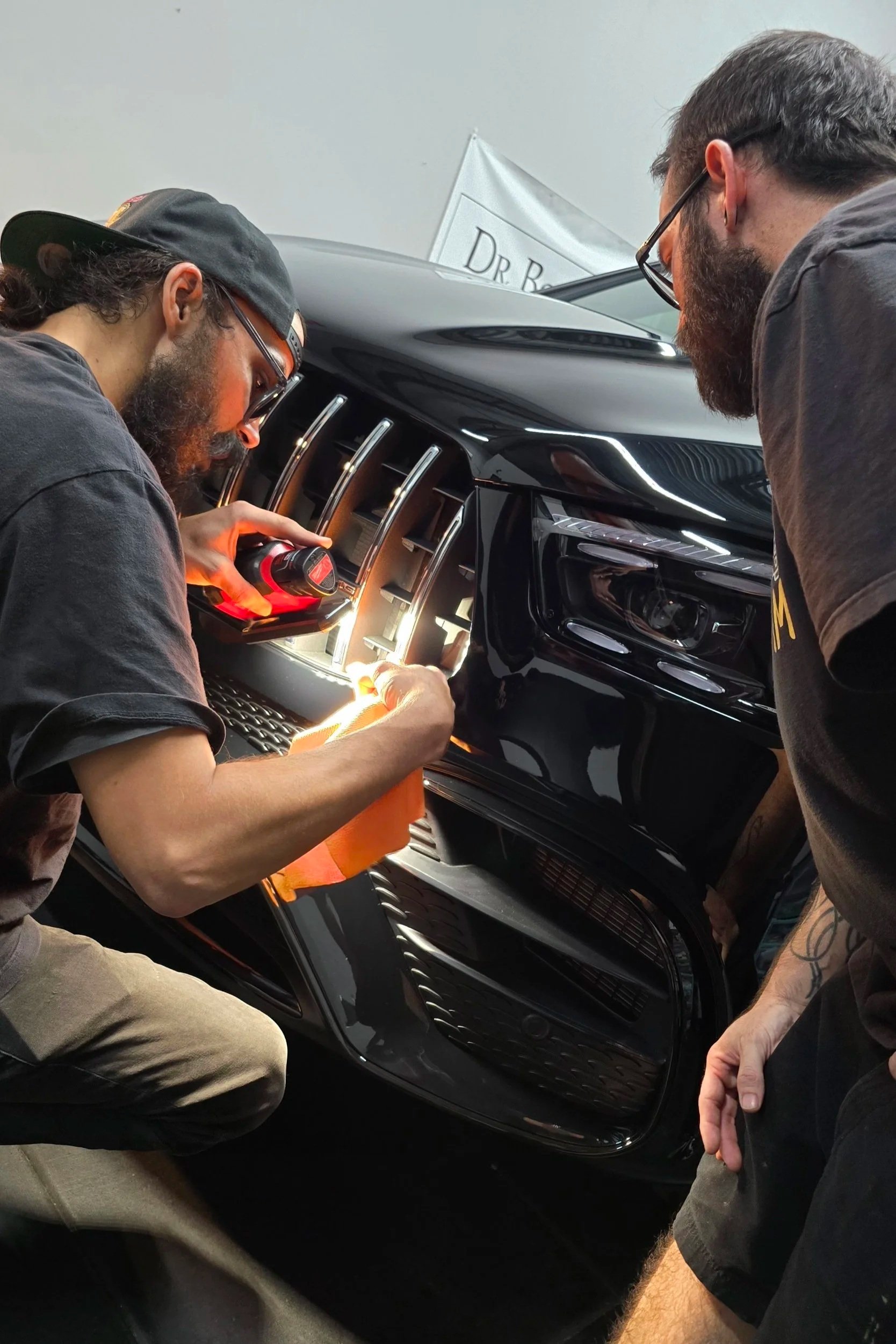 Applying self-healing ceramic coating to the front bumper of a black Mercedes GLE63 at Miyagi Motorworks in Largo, FL