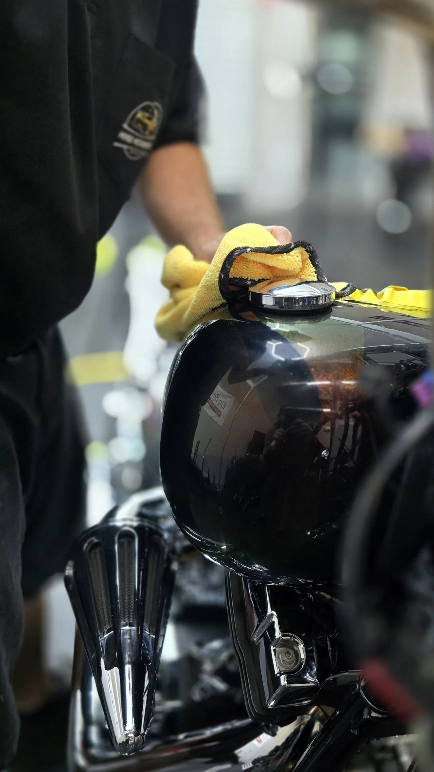 Owner of Miyagi Motorworks leveling a ceramic coating on a custom painted harley davidson gas tank inside ceramic coating studio