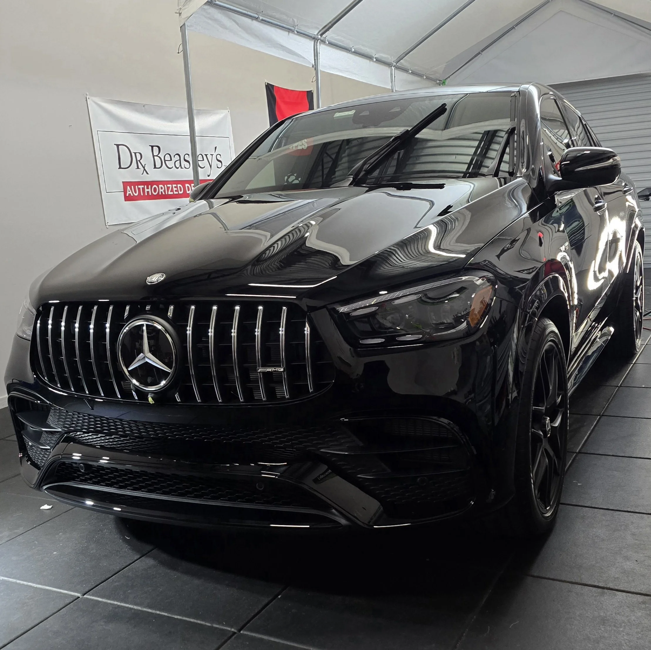 Black Mercedes-Benz GLE Coupe parked inside Miyagi Motorworks next to a Dr. Beasley's Authorized Detailer sign after a 25-year self-healing ceramic coating application.