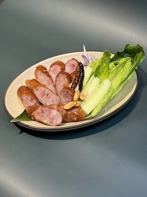 Thai Sausage
A flavorful, savory sausage made from minced pork, rice, and spices, fermented to give it that unique tangy taste. served with fresh veggies and chili