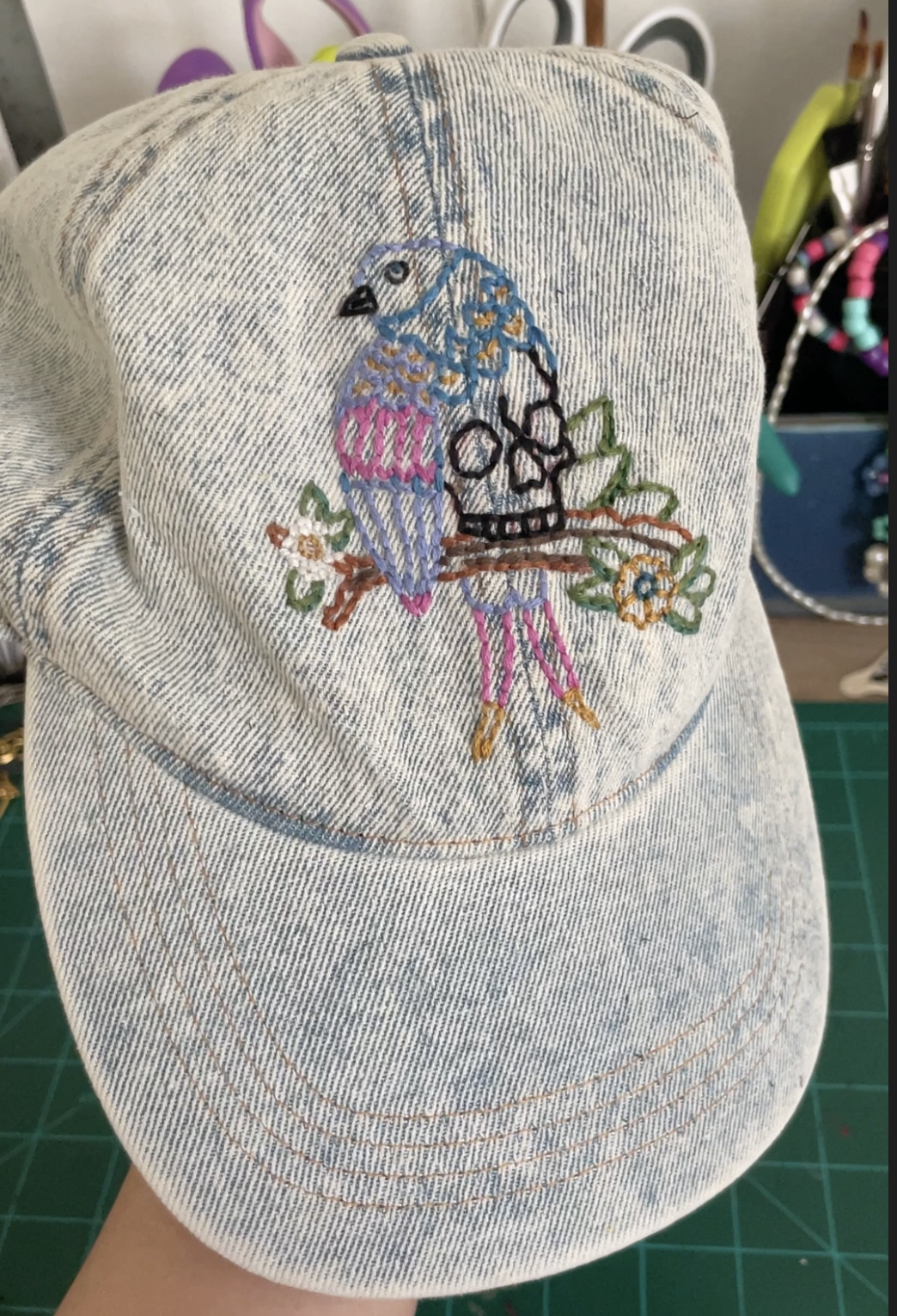 That Creative Space, art works , An artist's workspace with watercolor paints, brushes, colored pencils, a palette, and a watercolor portrait of a woman's face with green eyes on a white table.