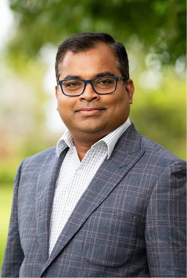 Dr Diss standing outdoors with a blurred green background.