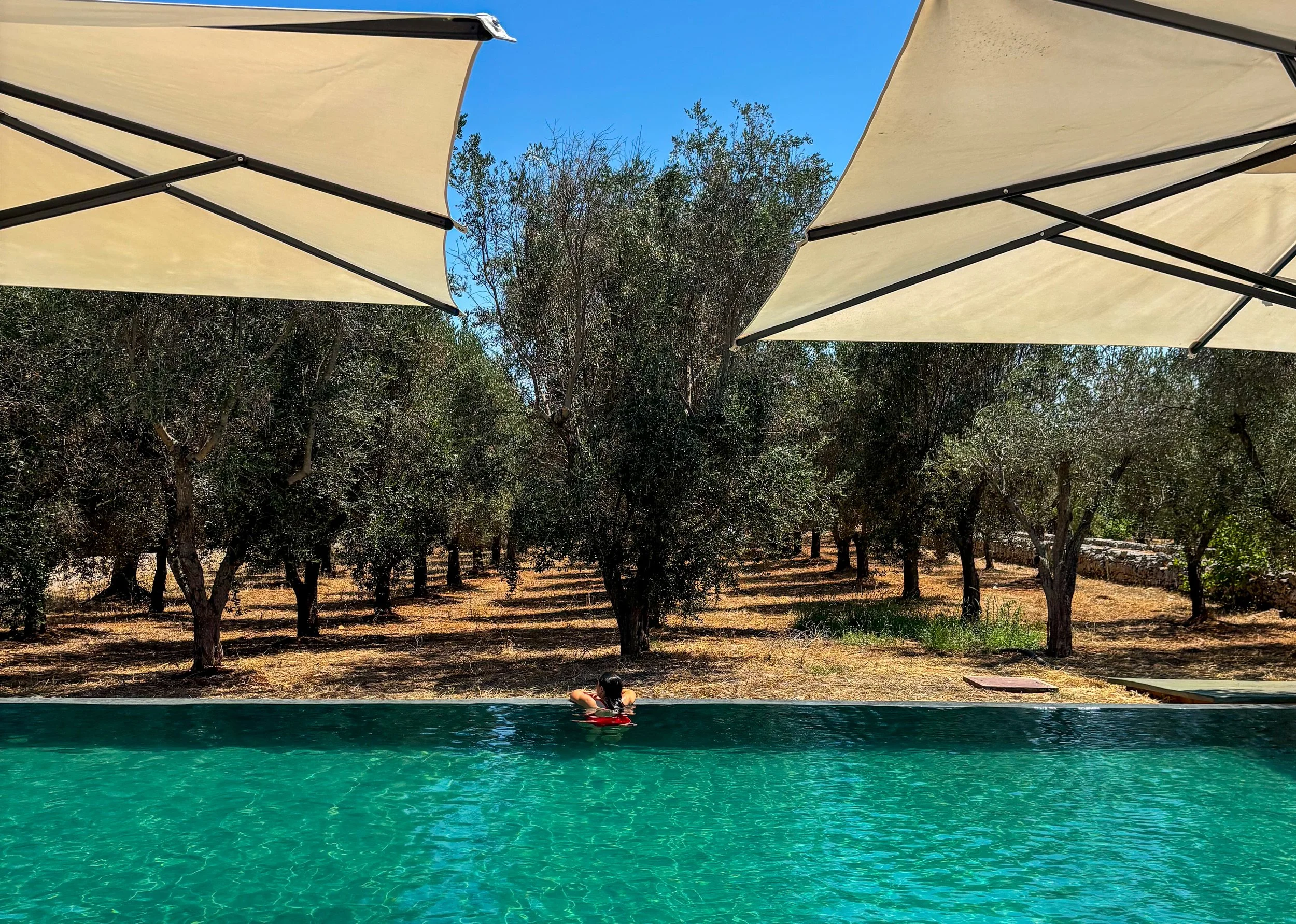 Two beach umbrellas and a lone swimmer at Casa Amahoro