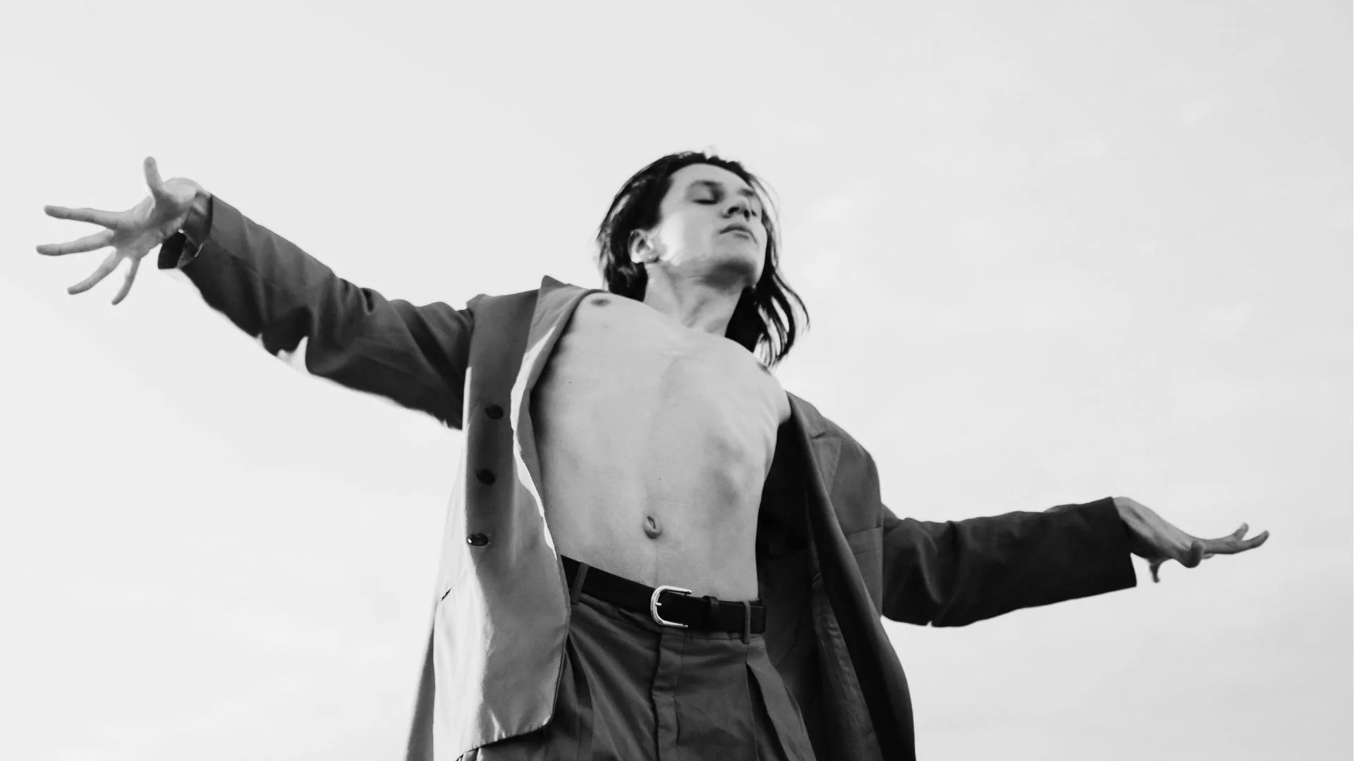 A queer person dancing with outreached hands.