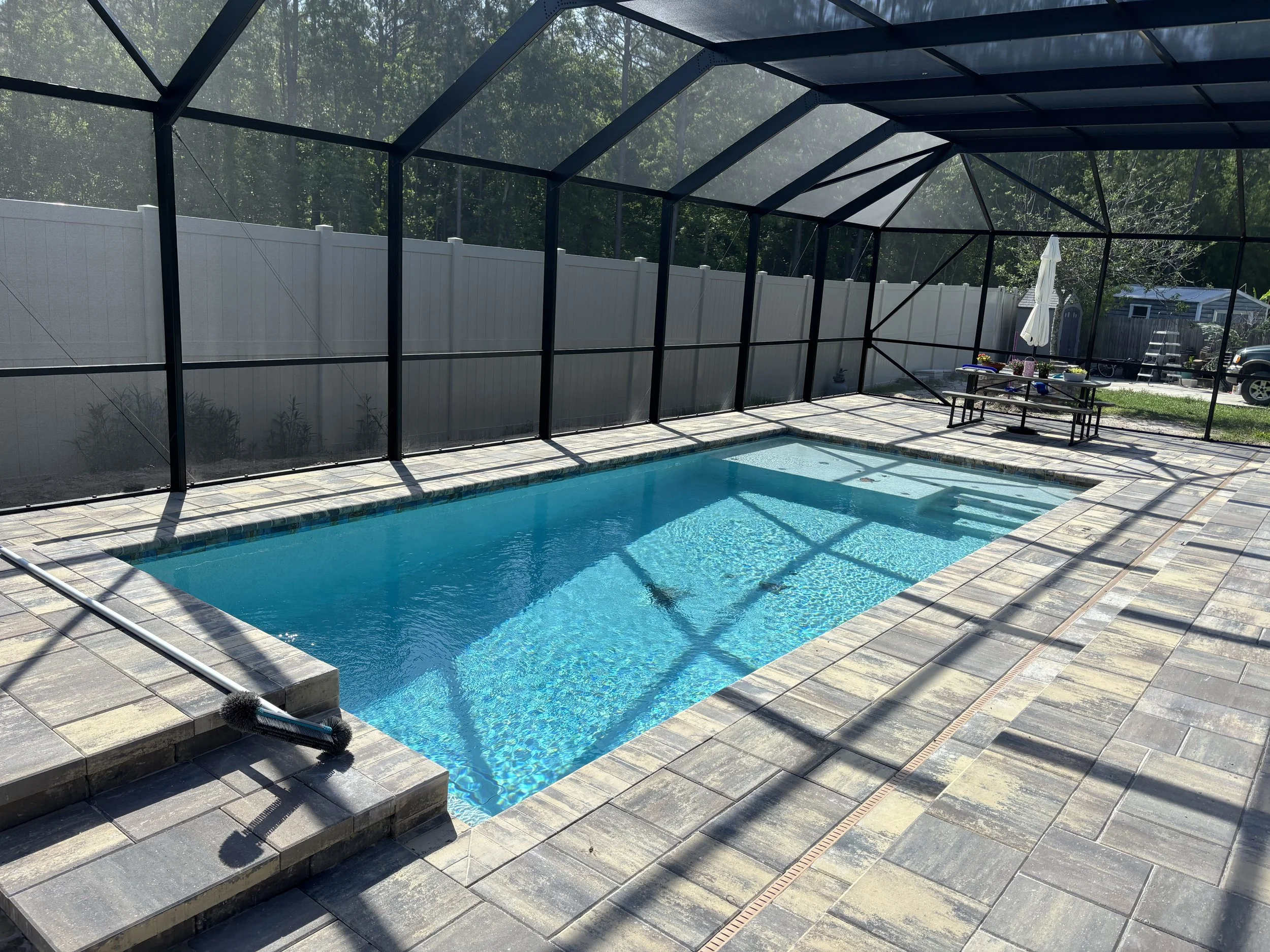 Screen-Enclosed Pool with Sun Shelf & Patio Lounge  Blue Water Outdoors  Butler Beach, FL
This custom rectangular pool by Blue Water Outdoors features a sleek, geometric layout enclosed within a screened structure for year-round comfort and protectio