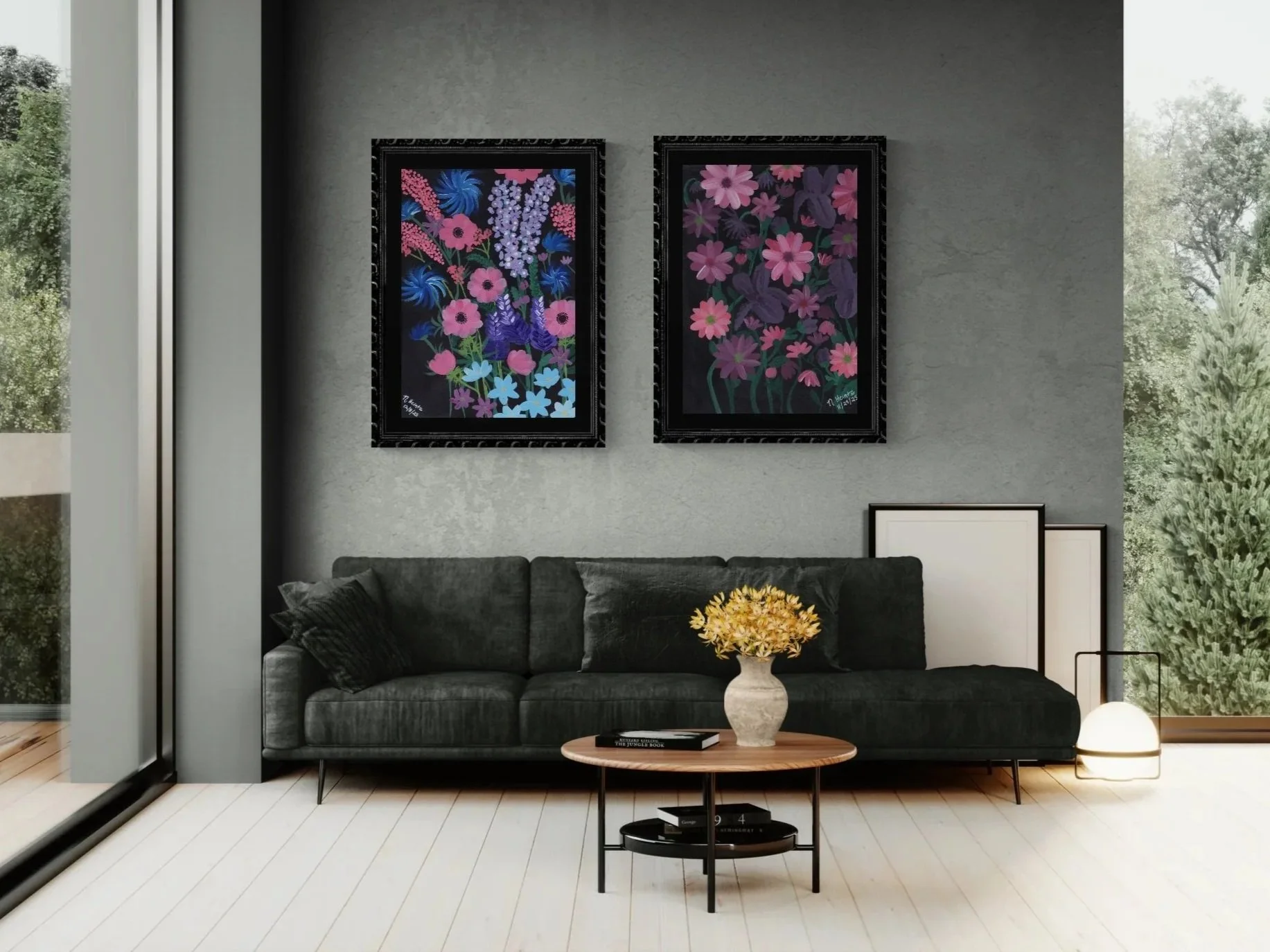 Two floral paintings with pink, purple and blue flowers on black backgrounds with black matte and frames above a dark couch.