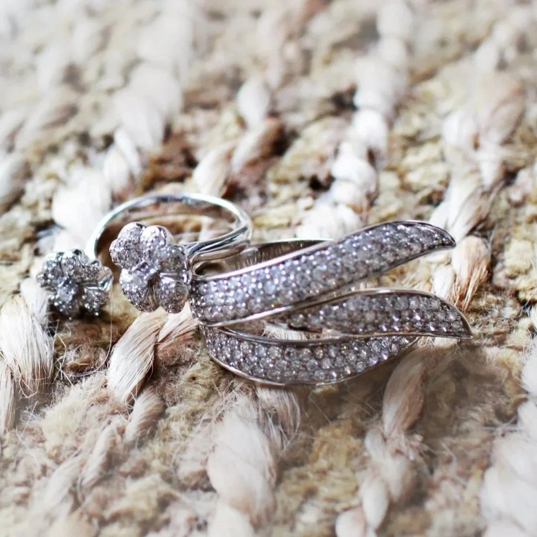 A large house with a sloped roof and multiple gables, surrounded by a landscaped yard with a stone-paved walkway, trees, and a lawn, under a partly cloudy sky.