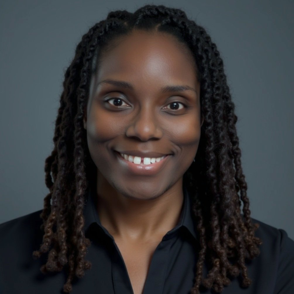 A smiling woman with long braids wearing a black shirt against a gray background.