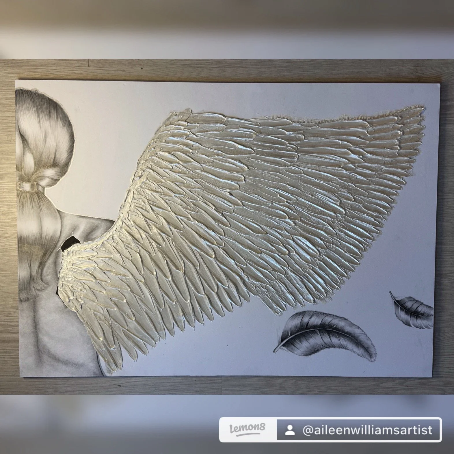 A mixed media artwork featuring a realistic drawing of a woman's upper body with a short hairstyle, combined with a metallic textured wing detail and additional black and white feathers.
