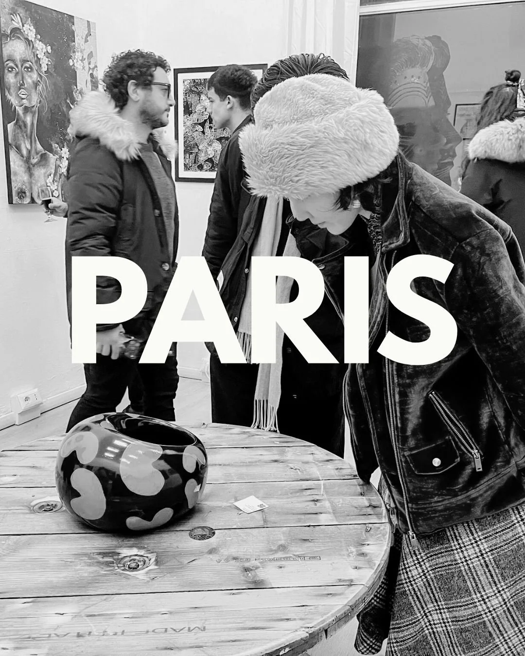People viewing artwork in an art gallery in Paris, black and white photo, a woman in a fur hat and leather jacket looking at a decorative vase on a wooden table.
