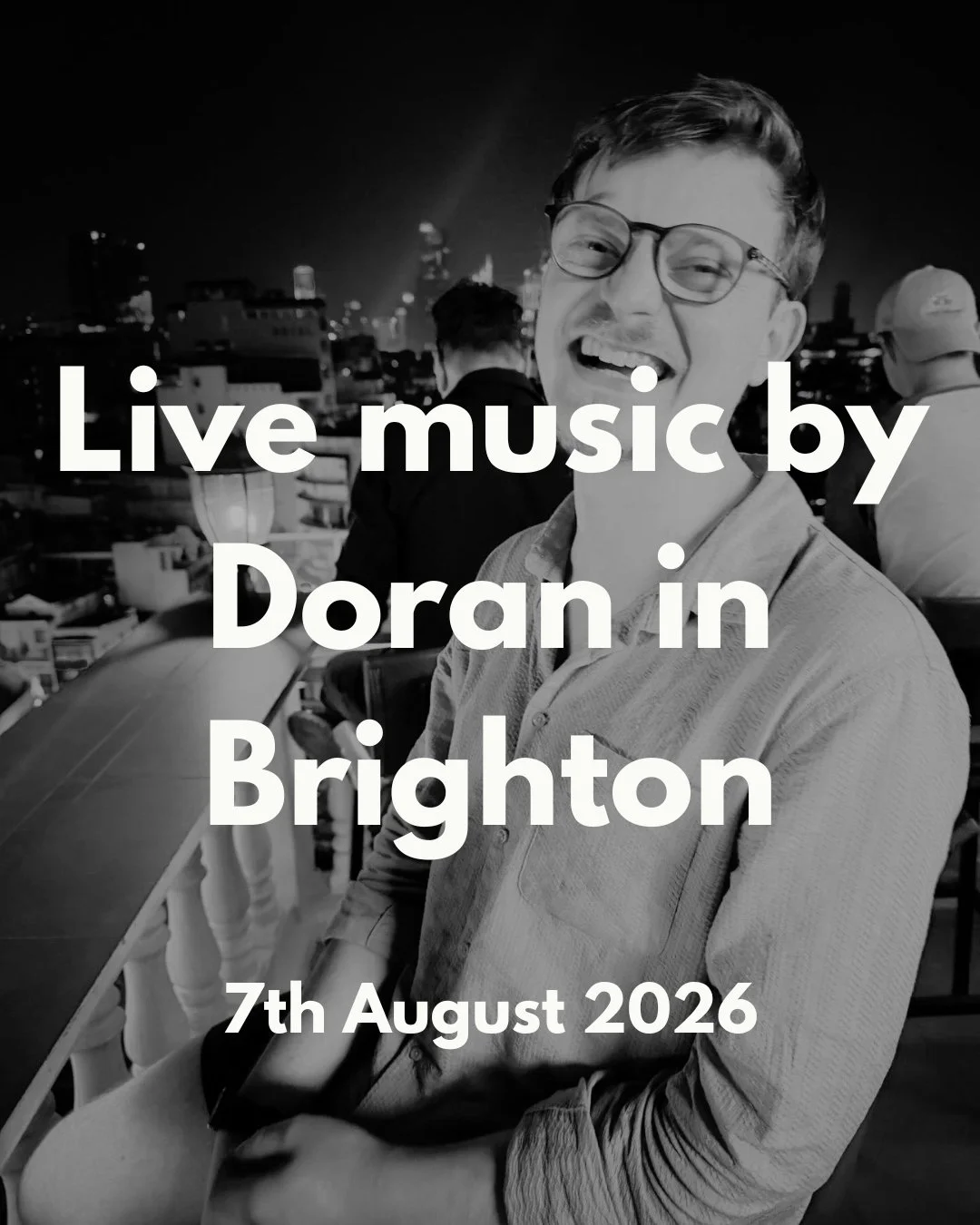 Promotional image for a live music event showing a smiling man wearing glasses at an outdoor rooftop venue at night, with a city skyline in the background. Overlaid text reads "Live music by Doran in Brighton, 7th August 2026."