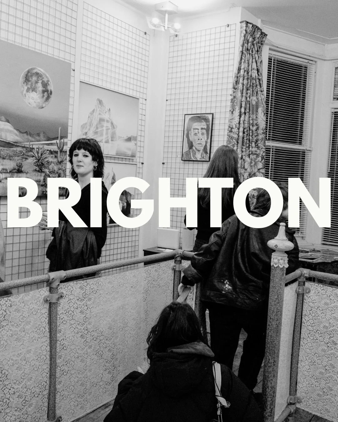Black and white photo of an art gallery with several people viewing paintings on the walls, some people with their backs to the camera and one woman facing the camera, with large text 'BRIGHTON' overlaid.