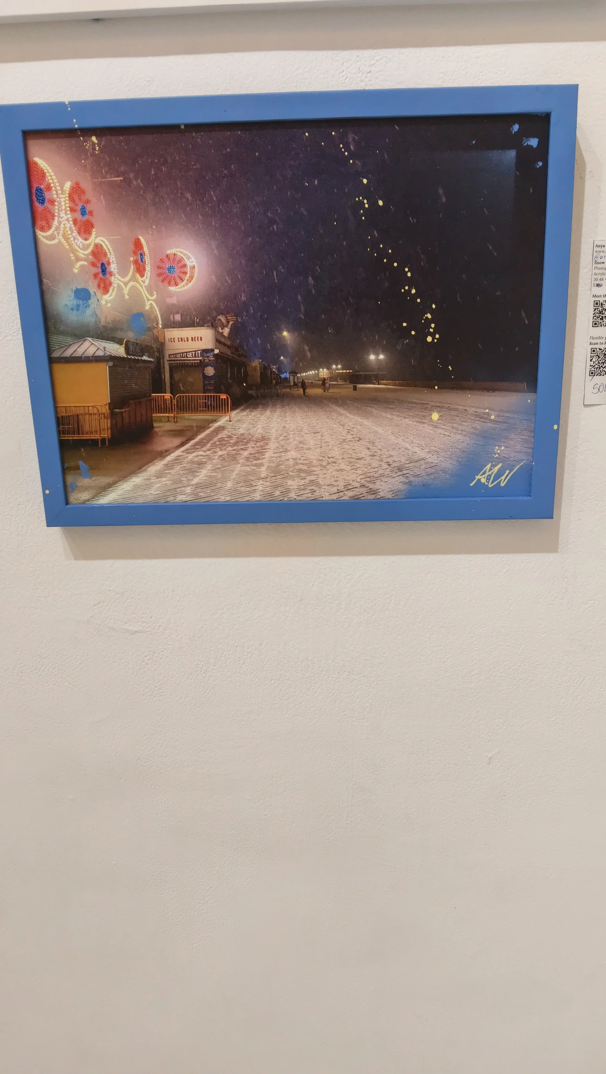 A nighttime scene at a fair or amusement park with colorful rides and bright lights, some of which are blurry due to motion or camera settings, and a snow-covered ground.