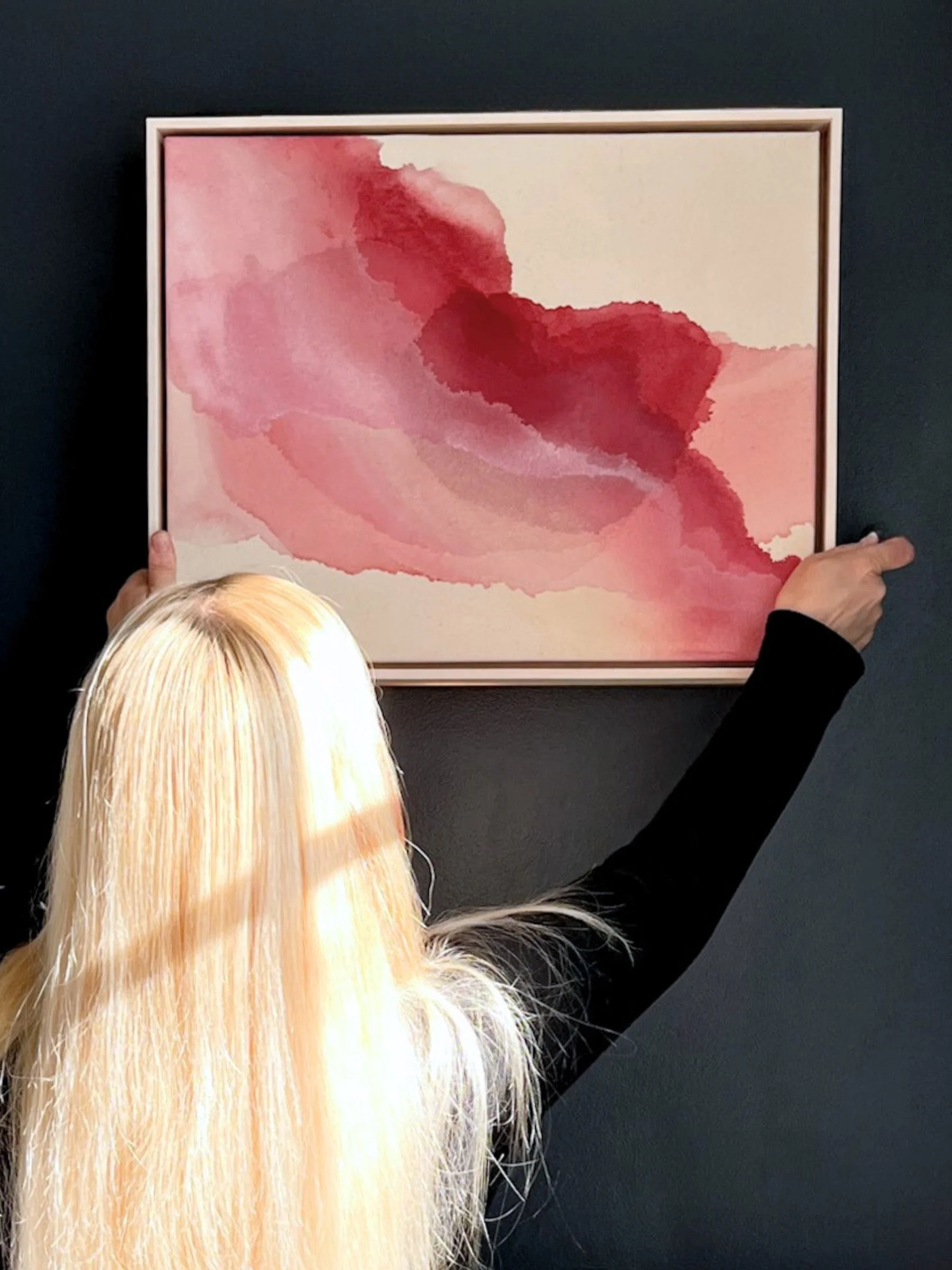 Crimson Tide abstract acrylic painting in red tones, held by artist against a dark wall—evoking layered motion and emotional clarity