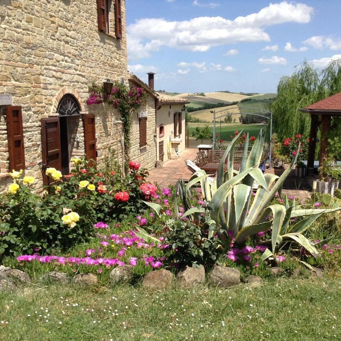 Stone house with landscaped garden and countryside views in Le Marche, Italy.