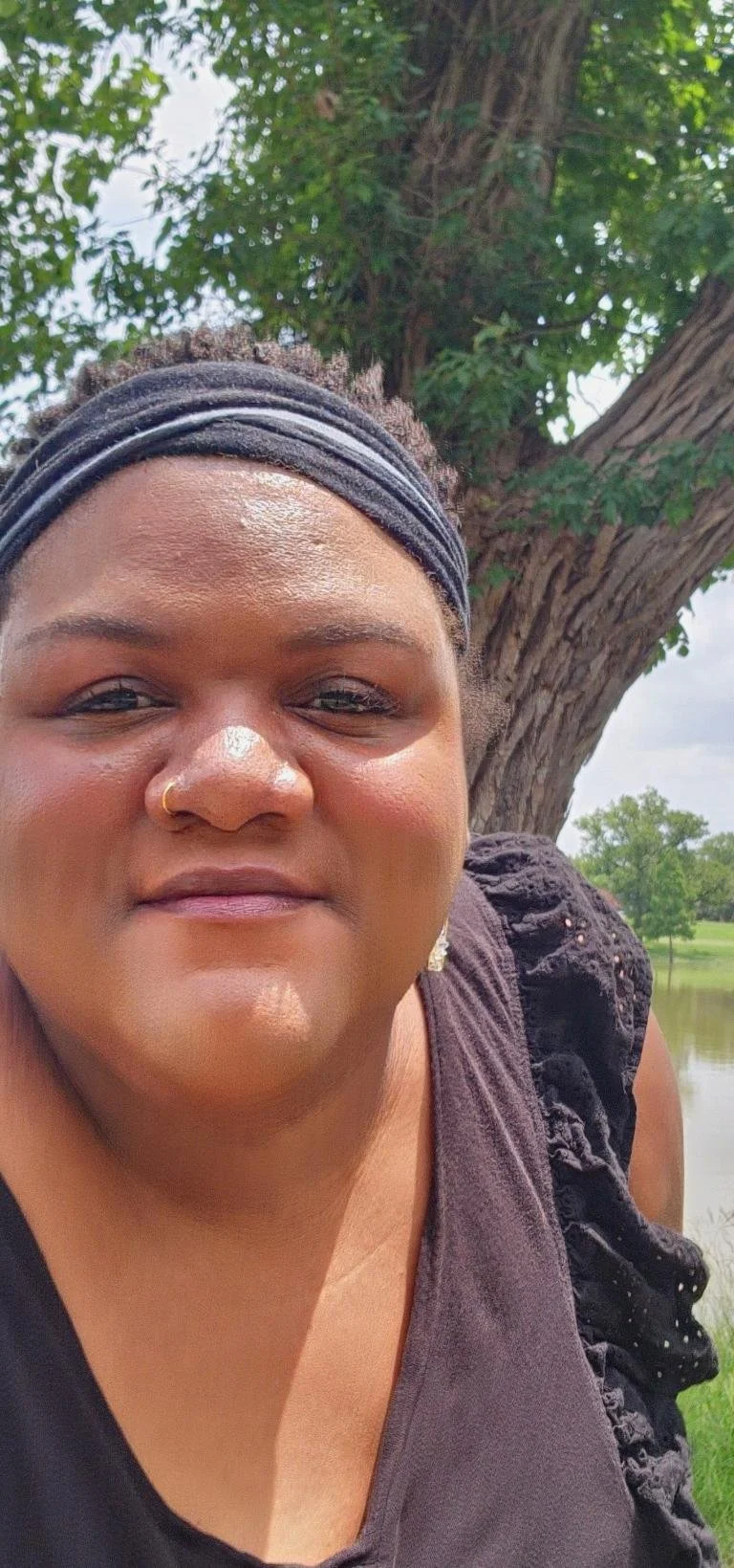 Close up on DeVon Moore's face, smiling. A tree is in the background by the lake.